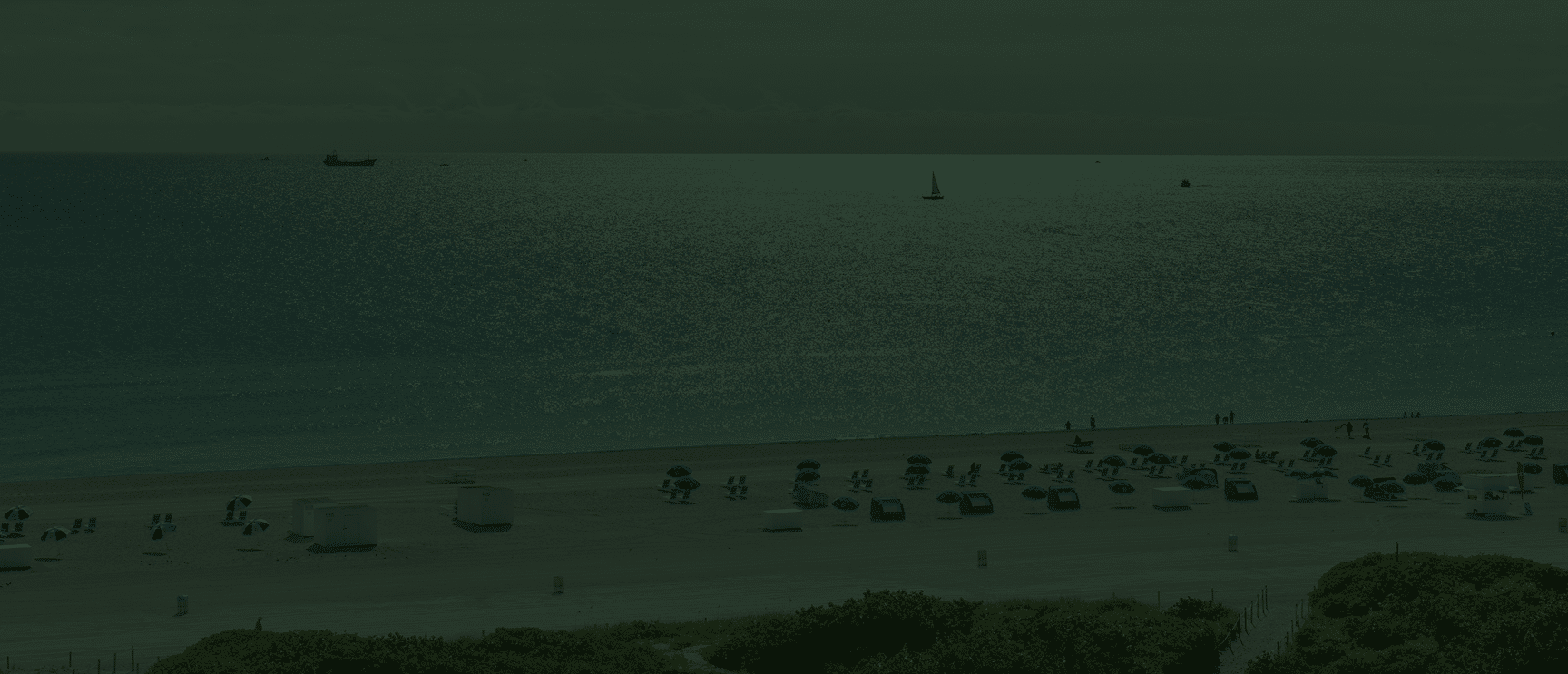 people on the beach and sailboats on the water in Miami